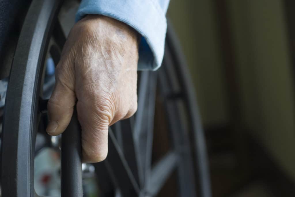 Senior hand on wheelchair wheel