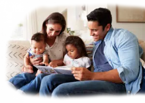 a father and mother reading a book to their two children