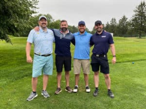 four men take a picture together on a golf course