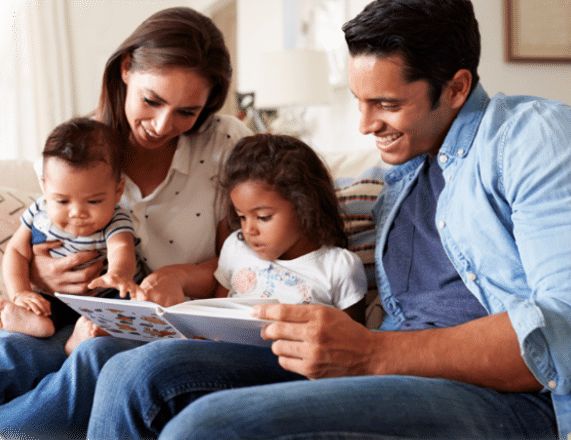 a mother and father reading to their children