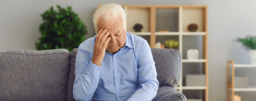 an elderly man holding his head