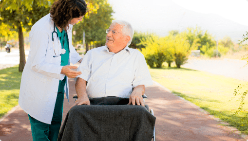 A female doctor talking to an elderly man on wheel chair