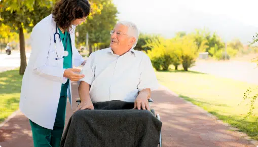 A female doctor talking to an elderly man on wheel chair