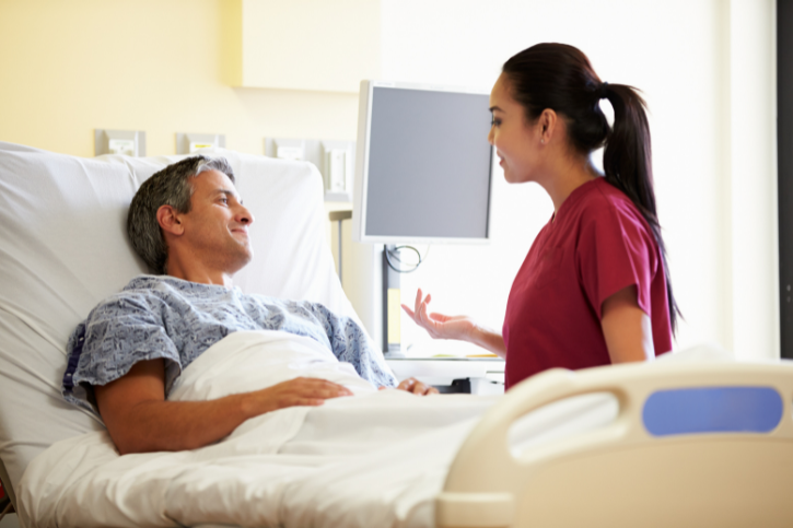 a nurse talking to a person laying in a hospital bed