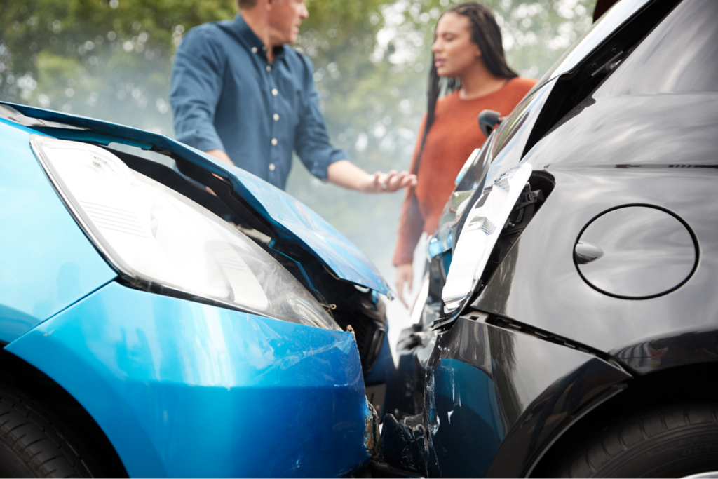 A man and woman standing next to a damaged car after an accident