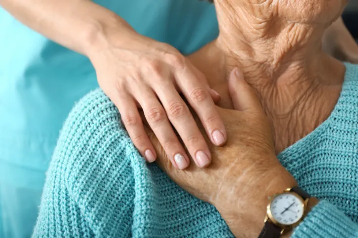 A nurse comforting a woman by holding her hand.