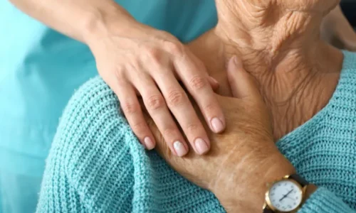 A nurse comforting a woman by holding her hand.