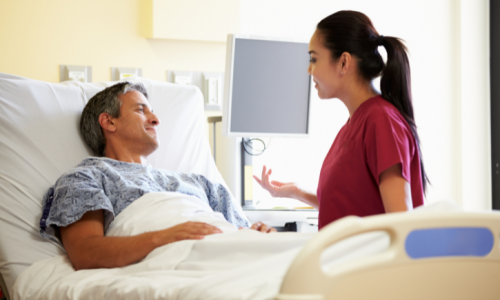 a nurse talking to a person laying in a hospital bed