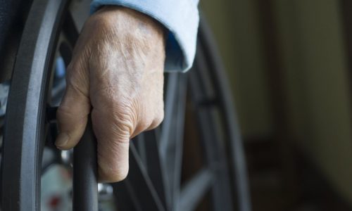 Senior hand on wheelchair wheel