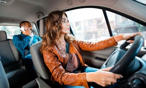 a female driver and a man at the back seat